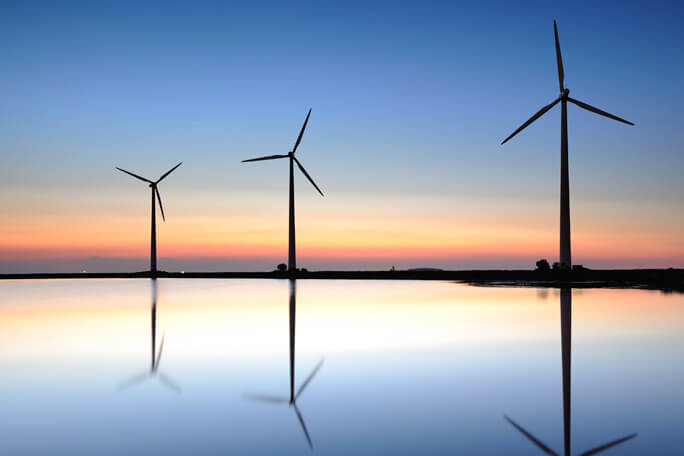 silhouettes of three wind turbines during sunset