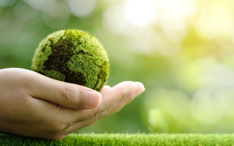 Close up of Hands Holding the Earth on a Green Background